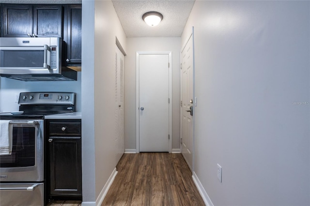 kitchen with appliances with stainless steel finishes, dark hardwood / wood-style flooring, and a textured ceiling