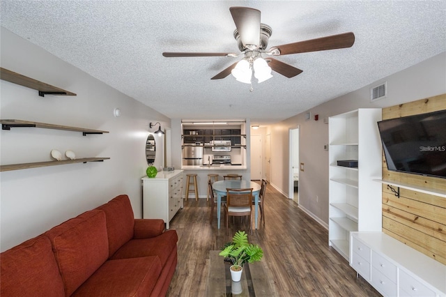 living room featuring ceiling fan, dark hardwood / wood-style flooring, and a textured ceiling