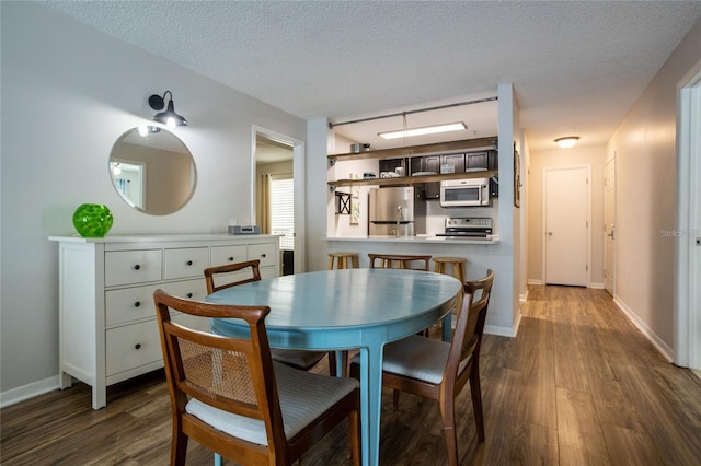 dining area with dark wood-type flooring and a textured ceiling