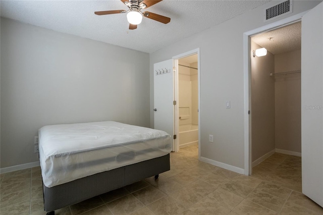 bedroom featuring a walk in closet, a textured ceiling, ceiling fan, and a closet