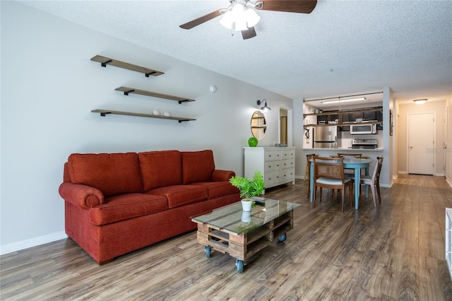 living room with hardwood / wood-style flooring, ceiling fan, and a textured ceiling