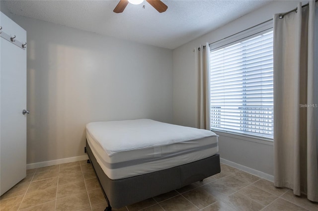 bedroom featuring a textured ceiling, ceiling fan, and light tile patterned flooring