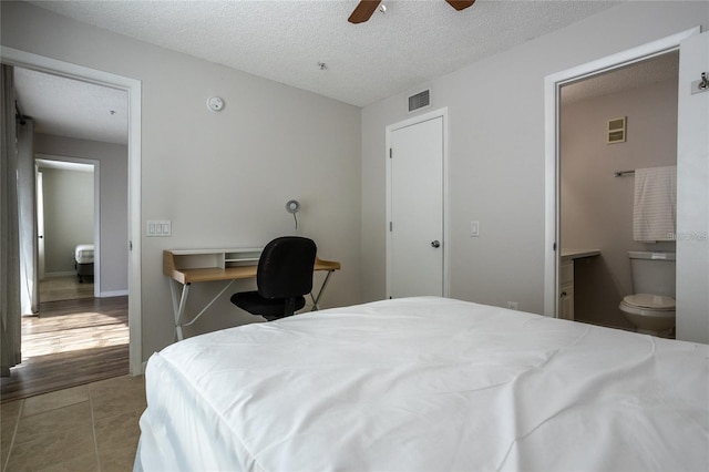 bedroom with tile patterned floors, connected bathroom, a textured ceiling, and ceiling fan