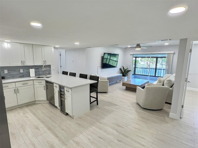 kitchen with tasteful backsplash, white cabinetry, sink, a breakfast bar area, and kitchen peninsula