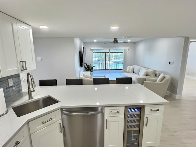 kitchen featuring dishwasher, light stone countertops, sink, and white cabinets