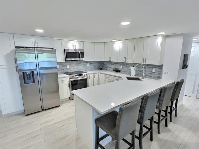 kitchen featuring stainless steel appliances, sink, a breakfast bar, and kitchen peninsula