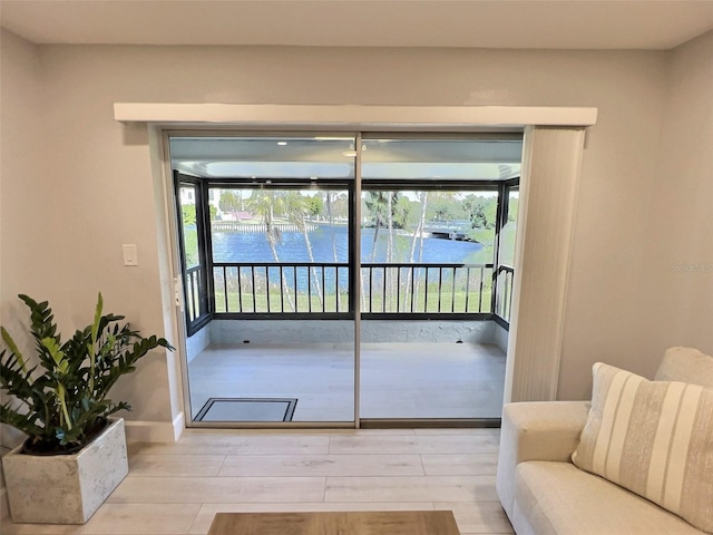 doorway to outside with light wood-type flooring and a water view