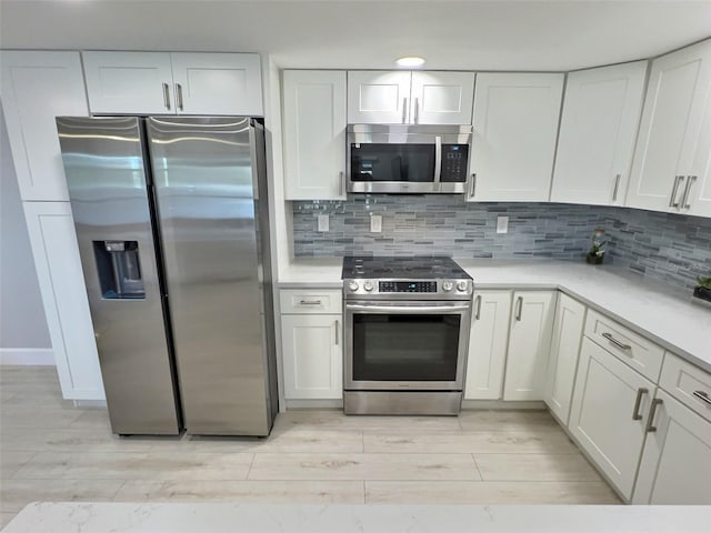 kitchen featuring white cabinetry, appliances with stainless steel finishes, backsplash, and light hardwood / wood-style floors