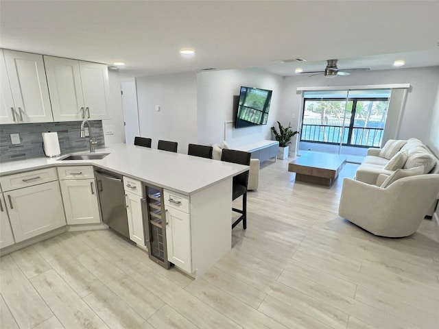 kitchen with sink, white cabinetry, a kitchen breakfast bar, dishwasher, and kitchen peninsula