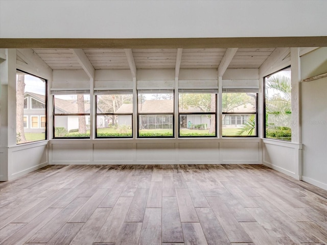 unfurnished sunroom featuring beamed ceiling, wood ceiling, and plenty of natural light