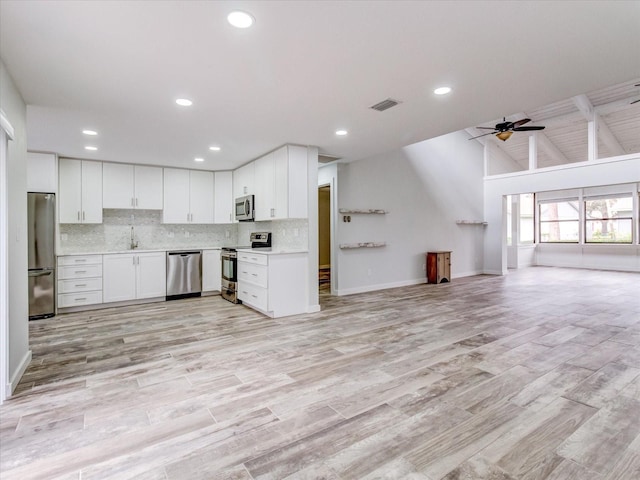 kitchen featuring white cabinetry, lofted ceiling, backsplash, ceiling fan, and stainless steel appliances