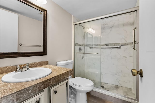 bathroom featuring a shower with door, vanity, and toilet