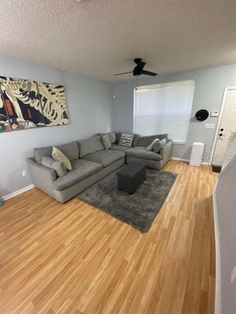 living room featuring ceiling fan, a textured ceiling, and light hardwood / wood-style flooring