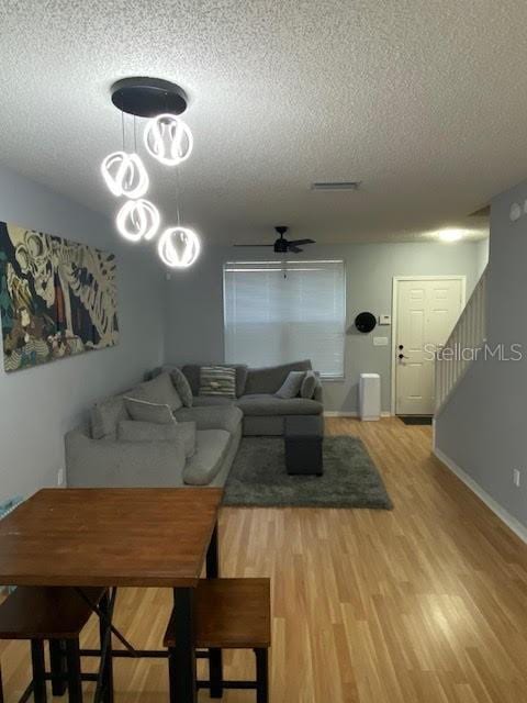 living room with wood-type flooring, a textured ceiling, and ceiling fan