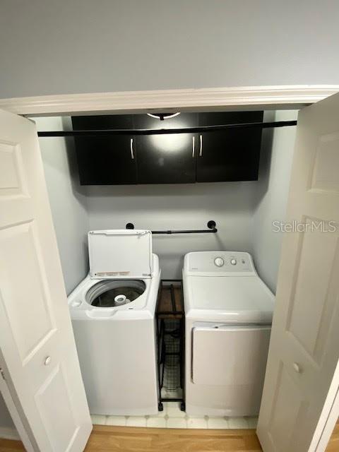 clothes washing area with washer and dryer, cabinets, and light hardwood / wood-style floors