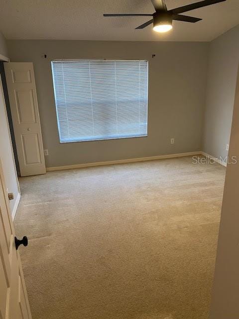 carpeted spare room featuring ceiling fan