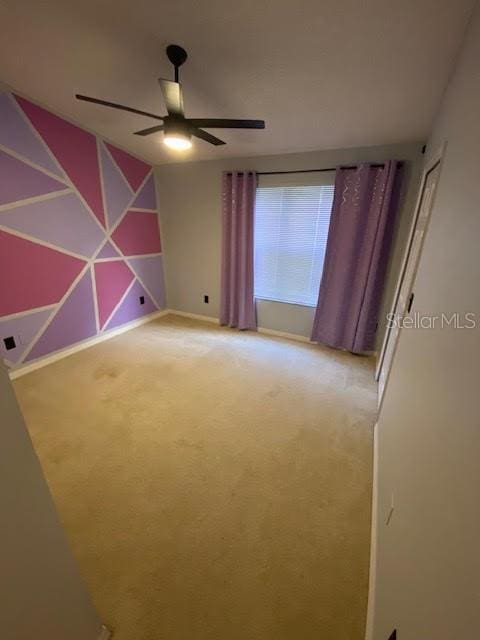 spare room featuring light colored carpet and ceiling fan