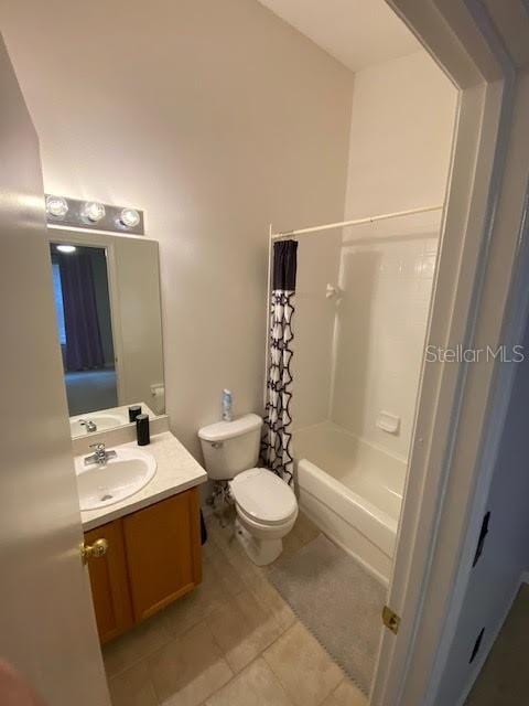 full bathroom with shower / bath combo with shower curtain, toilet, vanity, and tile patterned flooring