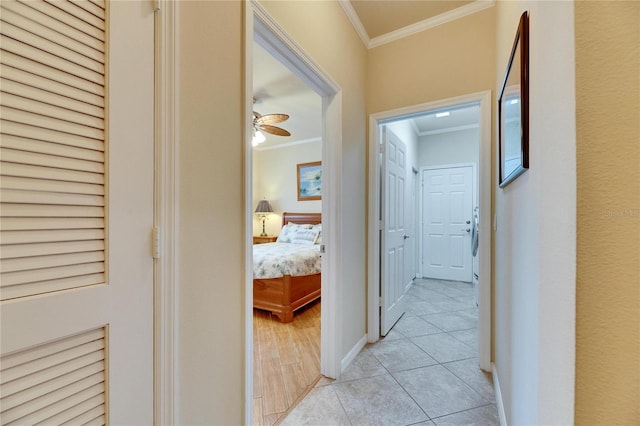 hall featuring light tile patterned floors and crown molding