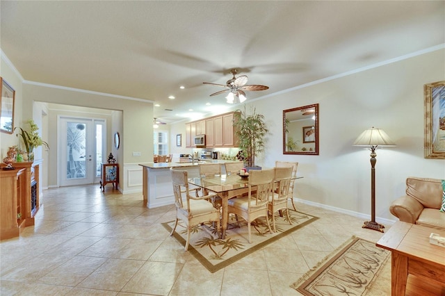 tiled dining space with ceiling fan, ornamental molding, and sink