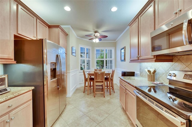 kitchen featuring light stone countertops, ornamental molding, appliances with stainless steel finishes, and ceiling fan