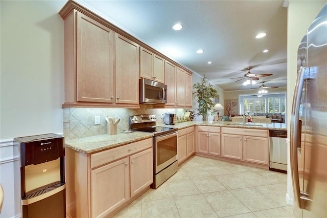 kitchen with appliances with stainless steel finishes, tasteful backsplash, sink, light stone countertops, and light brown cabinets