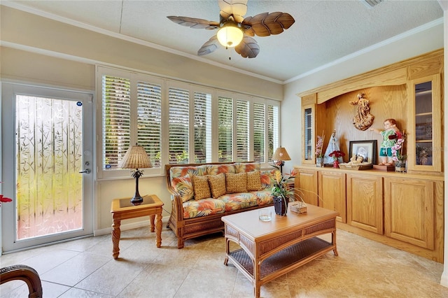 living room featuring ceiling fan, light tile patterned floors, ornamental molding, and a textured ceiling