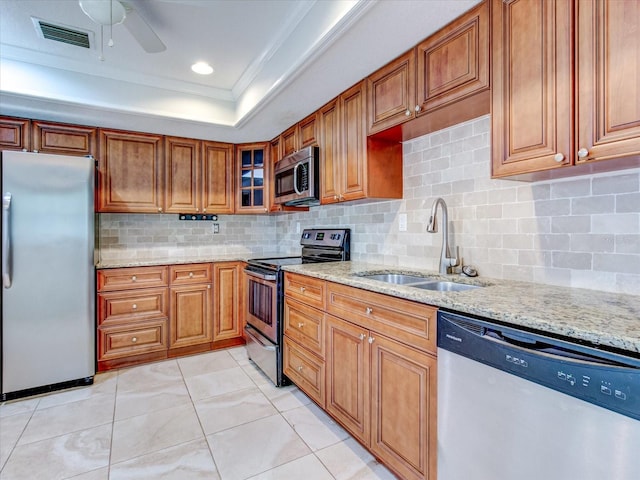 kitchen featuring sink, crown molding, stainless steel appliances, light stone countertops, and a raised ceiling