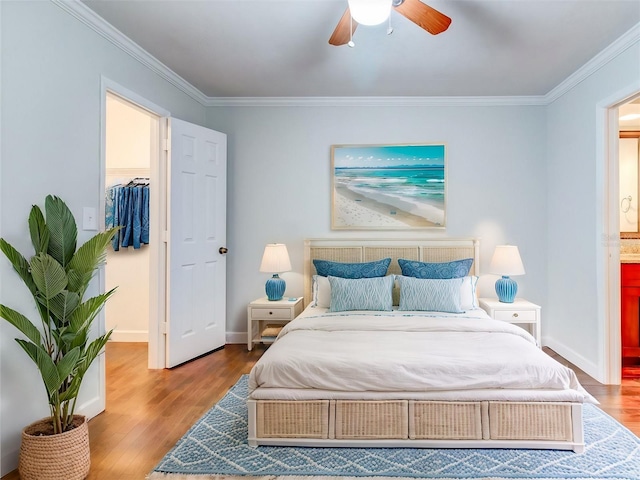 bedroom with ceiling fan, wood-type flooring, ornamental molding, a walk in closet, and a closet