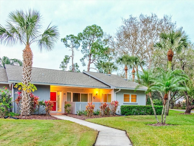 ranch-style home with a porch, a front yard, and a shingled roof