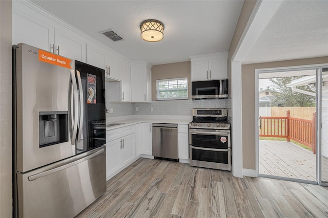 kitchen with white cabinetry, decorative backsplash, light wood-type flooring, and appliances with stainless steel finishes