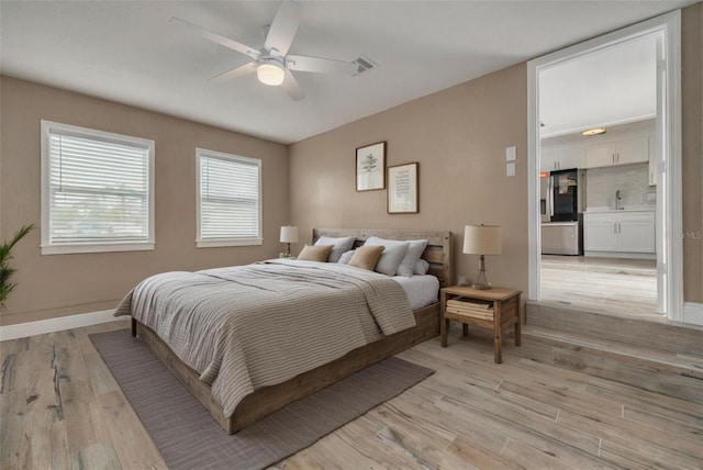 bedroom featuring ceiling fan, sink, stainless steel fridge with ice dispenser, and light hardwood / wood-style flooring