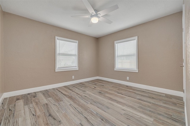 spare room featuring a wealth of natural light, light hardwood / wood-style floors, and ceiling fan