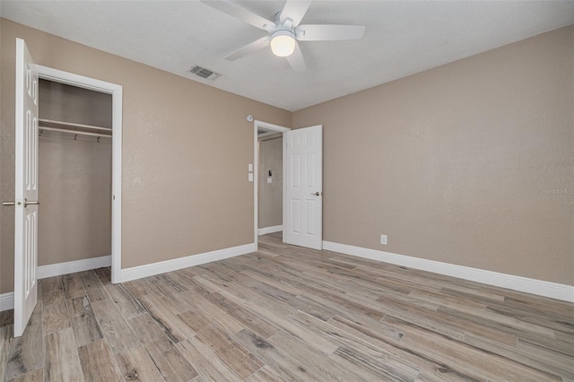 unfurnished bedroom with light hardwood / wood-style floors, ceiling fan, and a closet