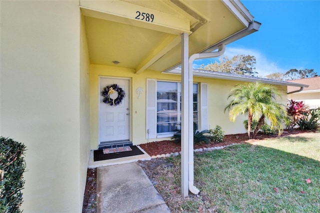2589 Redwood Cir, Clearwater, FL 33763 - view of exterior entry featuring stucco siding and a yard