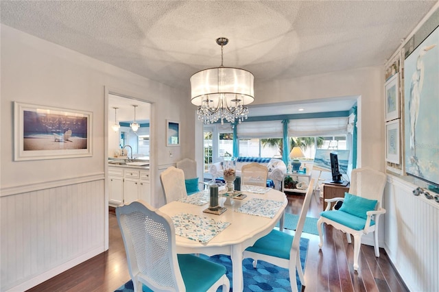 2589 Redwood Cir, Clearwater, FL 33763 - dining room with dark wood-type flooring, a textured ceiling, a chandelier, and a wainscoted wall