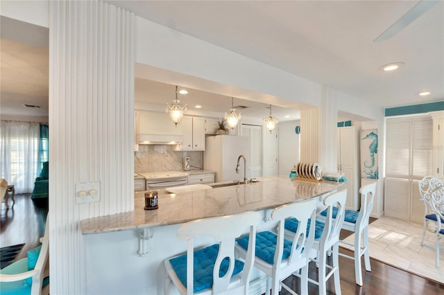 2589 Redwood Cir, Clearwater, FL 33763 - kitchen featuring freestanding refrigerator, a peninsula, backsplash, a breakfast bar area, and dark wood-style floors