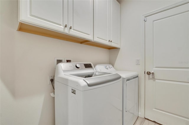 clothes washing area featuring cabinets and washing machine and dryer