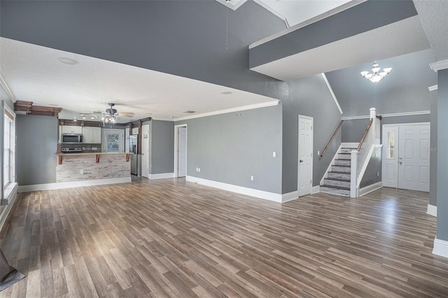 unfurnished living room with a high ceiling, crown molding, dark wood-type flooring, and ceiling fan with notable chandelier