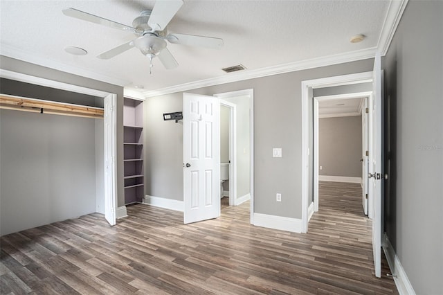 unfurnished bedroom featuring crown molding, a textured ceiling, dark hardwood / wood-style flooring, a closet, and ceiling fan