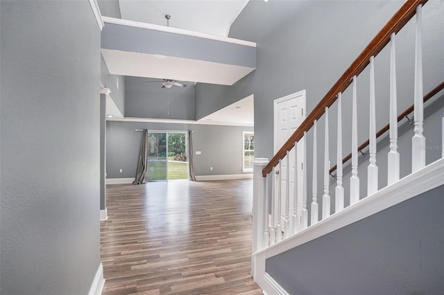 interior space with wood-type flooring, a towering ceiling, and ceiling fan