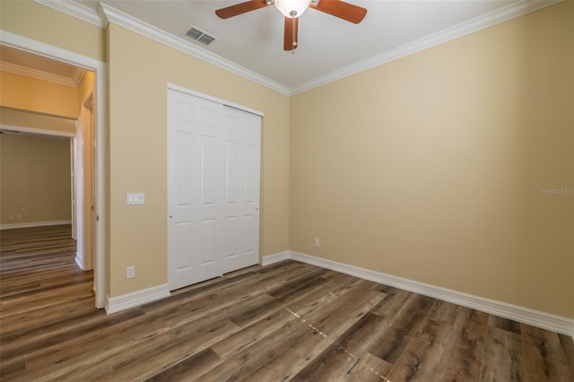 unfurnished bedroom featuring dark wood-type flooring, ceiling fan, ornamental molding, and a closet