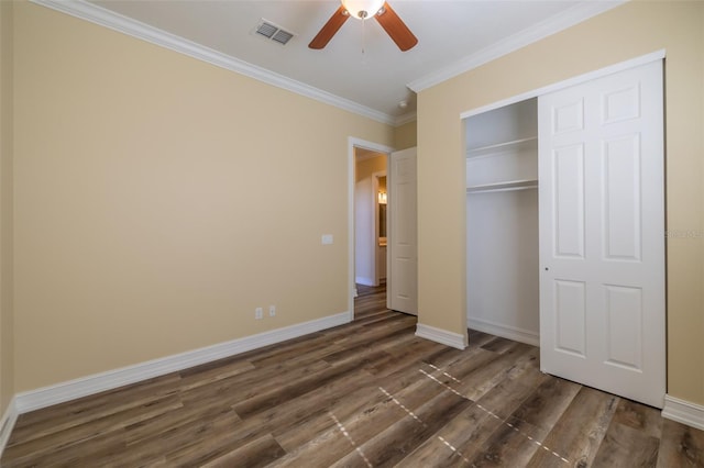 unfurnished bedroom featuring dark wood-type flooring, ornamental molding, a closet, and ceiling fan