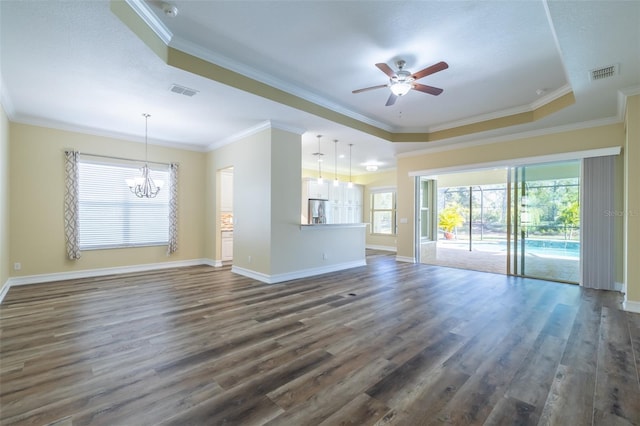 unfurnished living room featuring dark wood-type flooring, ornamental molding, a raised ceiling, and ceiling fan with notable chandelier