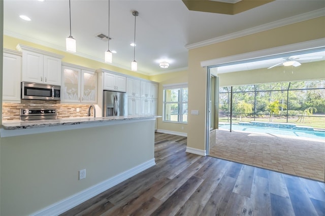 kitchen with pendant lighting, appliances with stainless steel finishes, white cabinetry, backsplash, and light stone countertops