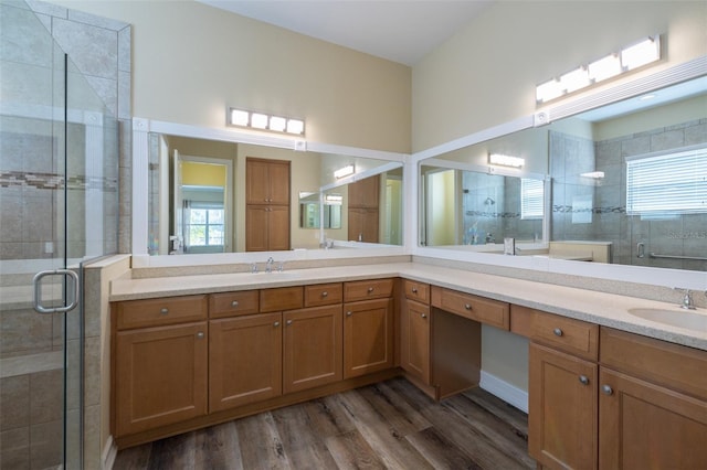 bathroom with wood-type flooring, a shower with door, and vanity