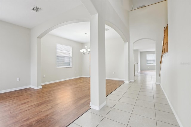 corridor featuring an inviting chandelier and light tile patterned floors