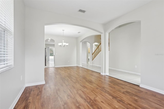 empty room featuring a chandelier and light hardwood / wood-style flooring