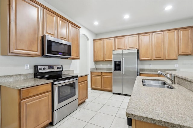 kitchen featuring light stone countertops, appliances with stainless steel finishes, sink, and light tile patterned floors