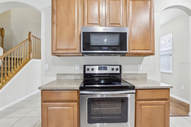 kitchen featuring stainless steel appliances, light tile patterned floors, and light stone counters